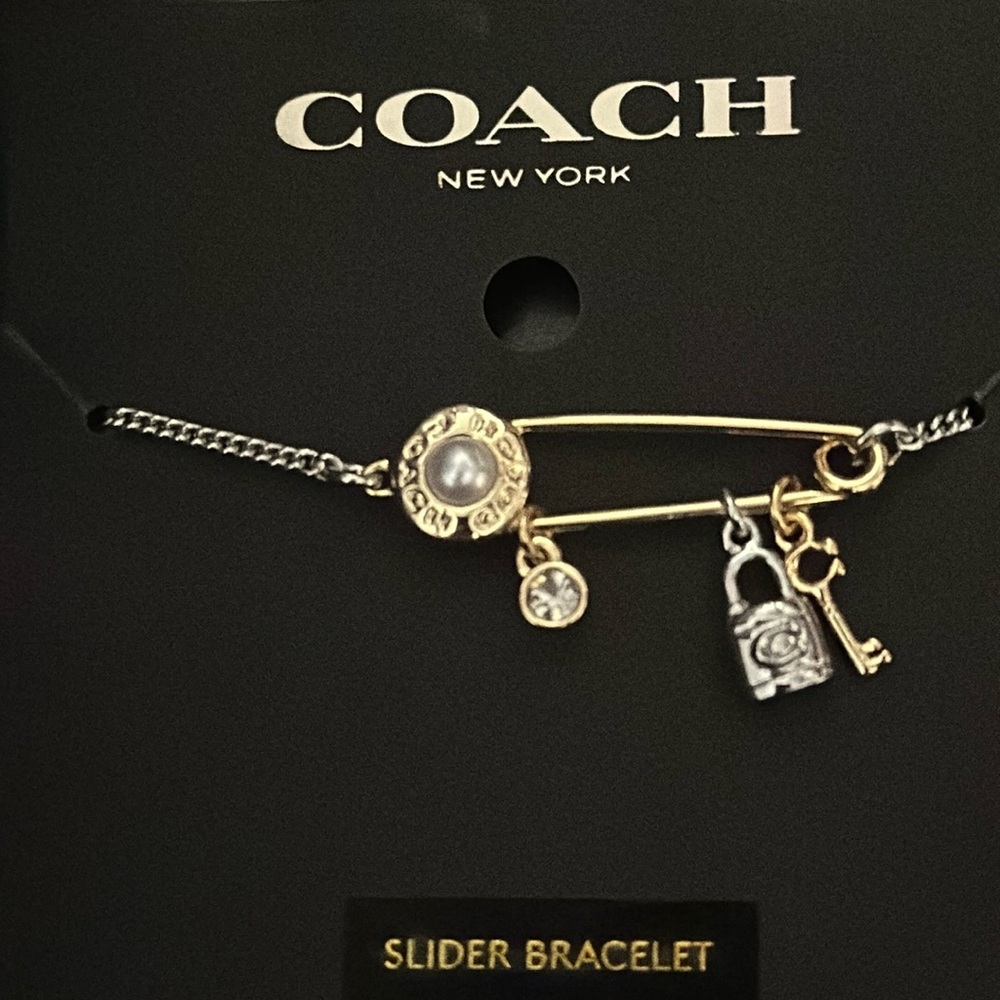 Coach gold and silver safety pin slider bracelet with charms.